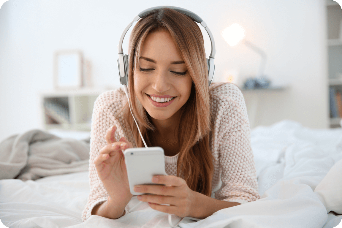 A woman relaxing in bed with her tunes.